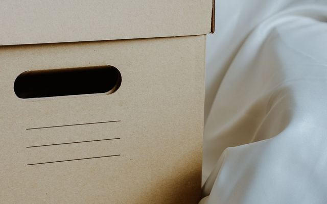 Caixa de papelão organizadora diante de um tecido branco