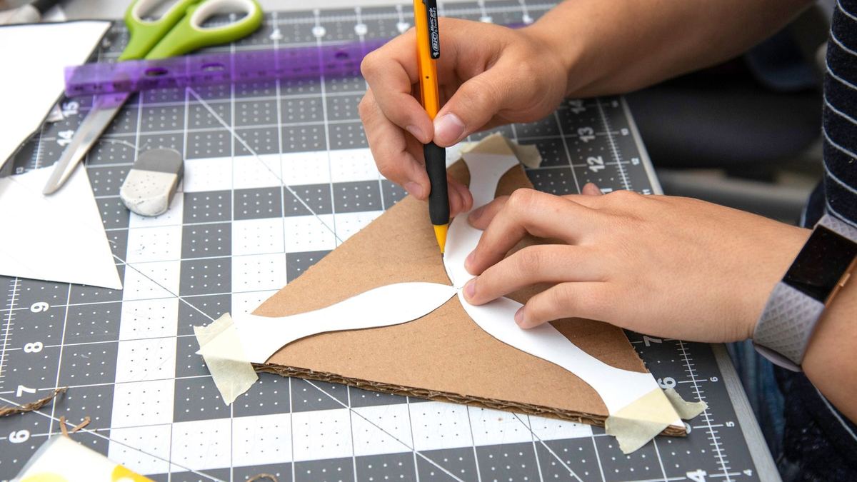 Pessoa recortando papelão e papel sobre uma base de corte