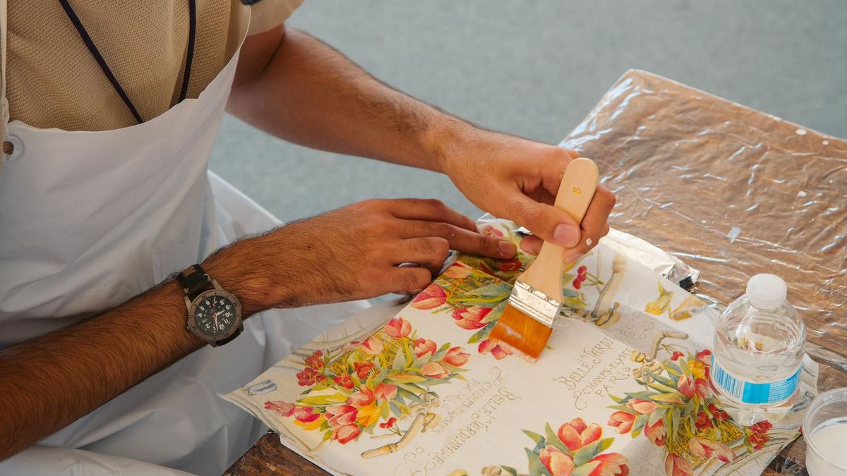 Pessoa aplicando cola em papel floral durante um trabalho de decoupage