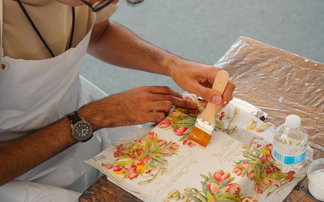 Pessoa aplicando cola em papel floral durante um trabalho de decoupage