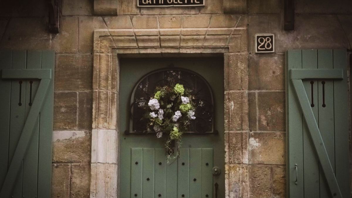 Porta verde rústica decorada com uma guirlanda