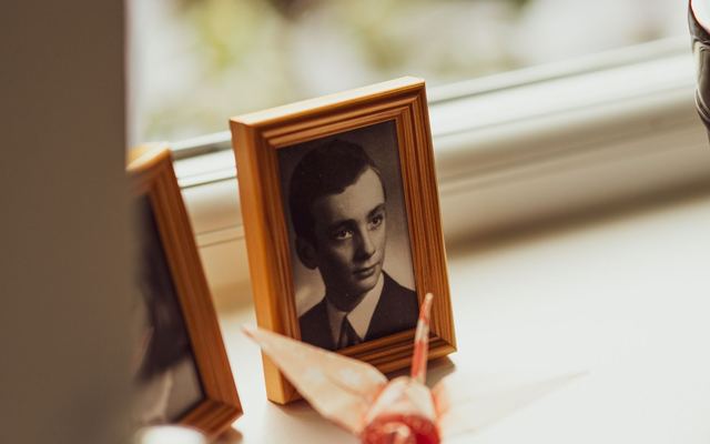Porta-retratos com foto antiga sobre um parapeito, ao lado de origamis coloridos