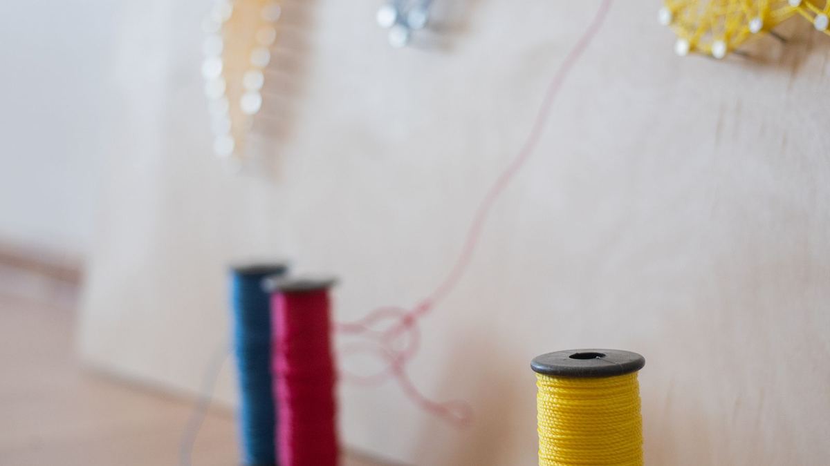 Quadro de string art com pregos e linhas coloridas sobre tábua de madeira